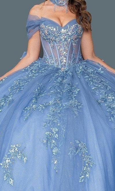 A woman wears the Quinceanera Dress 5156 By Dancing Queen, showcasing an off-shoulder design, sheer corset bodice, floral embroidery, and a glitter tulle ball gown skirt against a plain background.